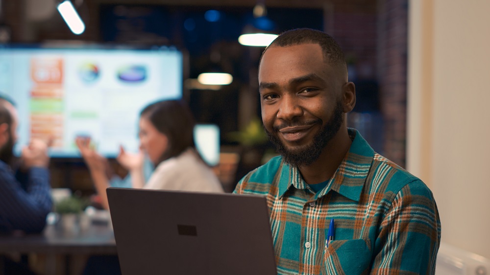 Smiling african american office employee working on laptop portrait